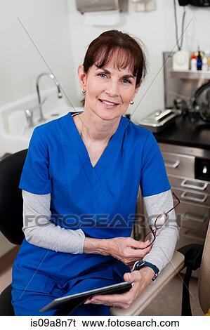 Senior doctor in blue scrubs holding medical chart, portrait View Large Photo Image Stock Photograph - Senior doctor in blue scrubs holding medical chart, portrait. Fotosearch