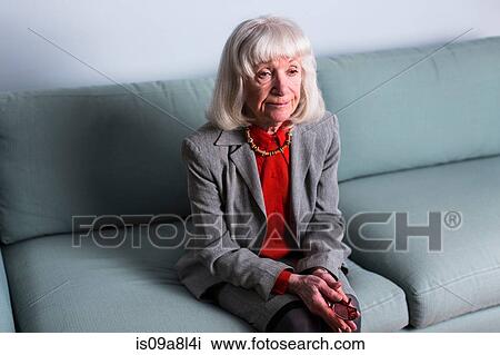 Senior woman sitting on sofa with blank expression View Large Photo Image Stock Image - Senior woman sitting on sofa with blank expression. Fotosearch
