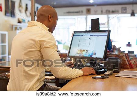 Shopkeeper using computer in vintage shop View Large Photo Image Stock Image - Shopkeeper using computer in vintage shop. Fotosearch