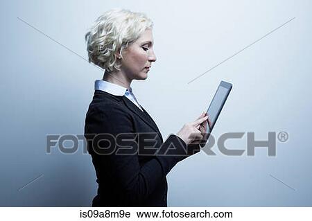 Studio portrait of blond businesswoman looking at digital tablet View Large Photo Image Stock Image - Studio portrait of blond businesswoman looking at digital tablet. Fotosearch