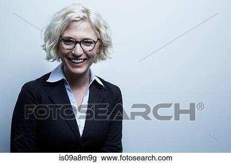 Stock Image - Studio portrait of blond businesswoman smiling. Fotosearch