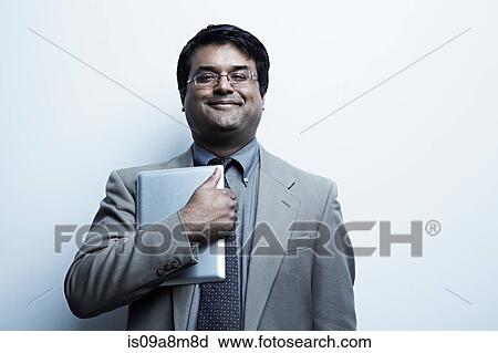 Stock Image - Studio portrait of businessman holding digital tablet. Fotosearch