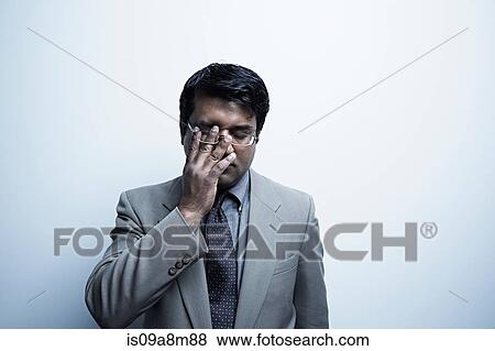 Studio portrait of businessman rubbing his eye View Large Photo Image Stock Photo - Studio portrait of businessman rubbing his eye. Fotosearch