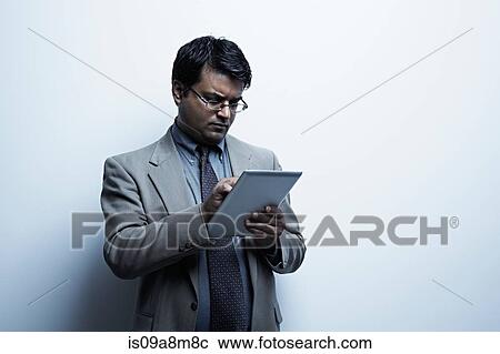Stock Image - Studio portrait of businessman with digital tablet. Fotosearch