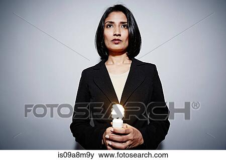 Studio portrait of businesswoman holding energy saving lightbulb View Large Photo Image Stock Photo - Studio portrait of businesswoman holding energy saving lightbulb. Fotosearch