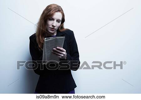Studio portrait of young businesswoman holding newspaper View Large Photo Image Picture - Studio portrait of young businesswoman holding newspaper. Fotosearch