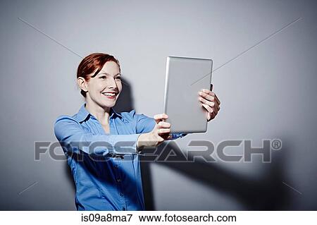 Studio portrait of young woman holding up digital tablet View Large Photo Image Stock Photo - Studio portrait of young woman holding up digital tablet. Fotosearch