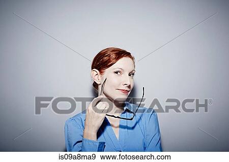 Studio portrait of young woman holding spectacles View Large Photo Image Stock Photo - Studio portrait of young woman holding spectacles. Fotosearch