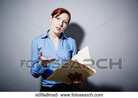 Stock Photography - Studio portrait of young woman holding folder. Fotosearch