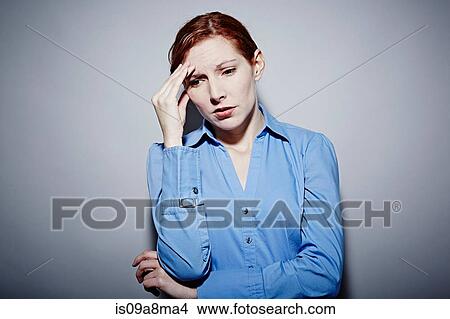 Studio portrait of young woman with hand on brow View Large Photo Image Picture - Studio portrait of young woman with hand on brow. Fotosearch