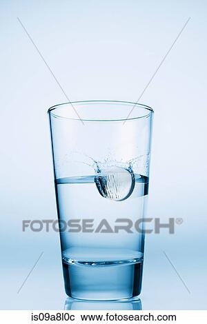 Stock Image - Tablet falling in glass of water. Fotosearch