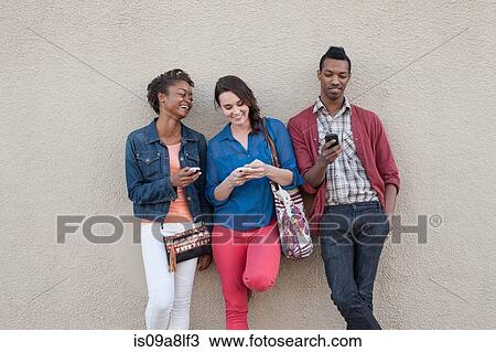Stock Image - Three friends using cell phones. Fotosearch