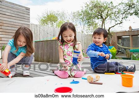 Picture - Three young children painting and drawing in garden. Fotosearch