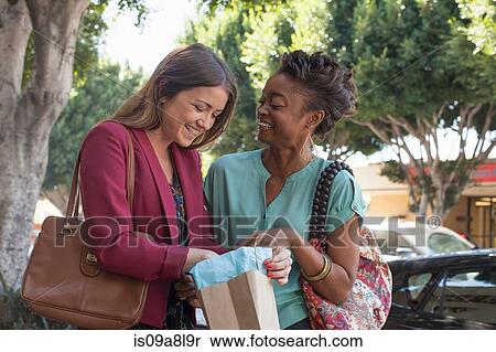 Two female friends shopping, one holding shopping bag View Large Photo Image Stock Photography - Two female friends shopping, one holding shopping bag. Fotosearch