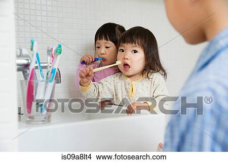 Two girls brushing teeth at bathroom sink View Large Photo Image Picture - Two girls brushing teeth at bathroom sink. Fotosearch