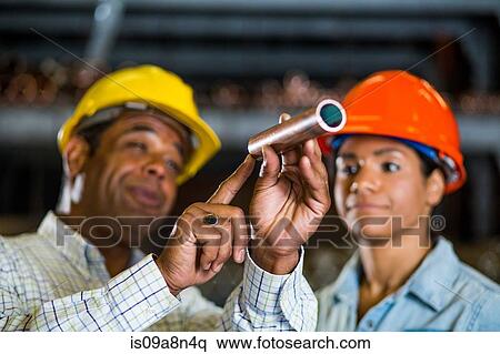 Two warehouse workers inspecting at copper pipe View Large Photo Image Stock Photography - Two warehouse workers inspecting at copper pipe. Fotosearch