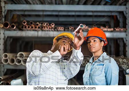 Stock Photography - Two warehouse workers looking at copper pipe. Fotosearch