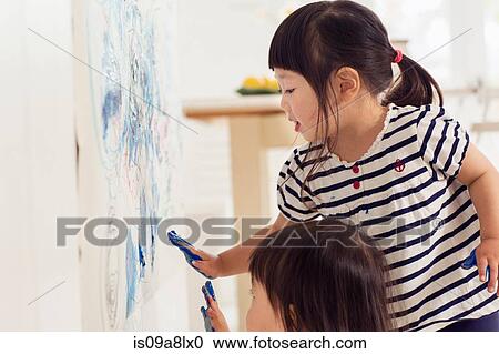 Stock Image - Two young sister making handprint painting. Fotosearch