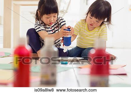 Two young sister squeezing paint from bottles View Large Photo Image Stock Photo - Two young sister squeezing paint from bottles. Fotosearch