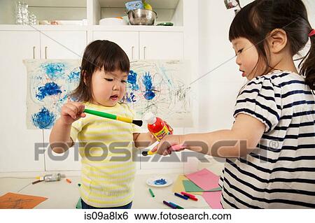 Two young sisters holding paint bottle and brushes View Large Photo Image Stock Photograph - Two young sisters holding paint bottle and brushes. Fotosearch