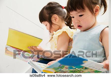 Two young sisters looking at picture books View Large Photo Image Picture - Two young sisters looking at picture books. Fotosearch