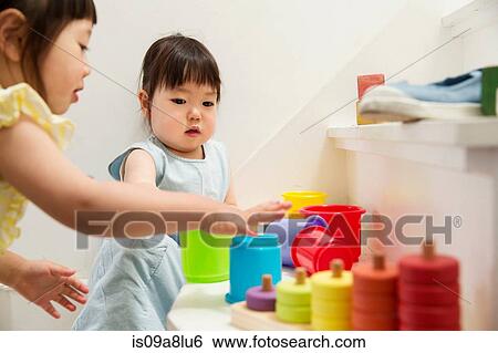 Two young sisters playing with toys on staircase View Large Photo Image Stock Photograph - Two young sisters playing with toys on staircase. Fotosearch