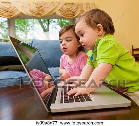 Two young toddlers playing with laptop View Large Photo Image Stock Photo - Two young toddlers playing with laptop. Fotosearch