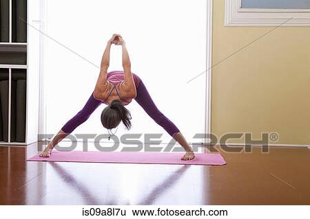 Stock Photograph - Woman bending forwards with arms raised. Fotosearch