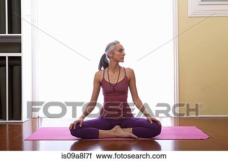 Woman doing yoga sitting cross legged, looking away View Large Photo Image Stock Image - Woman doing yoga sitting cross legged, looking away. Fotosearch