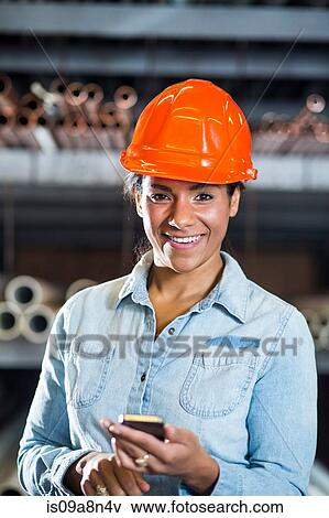 Stock Photo - Woman in warehouse holding smartphone. Fotosearch
