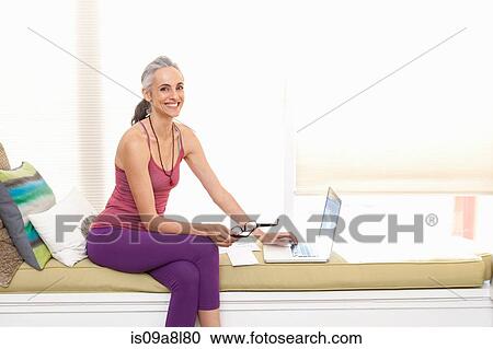 Woman sitting on window seat using laptop View Large Photo Image Stock Image - Woman sitting on window seat using laptop. Fotosearch