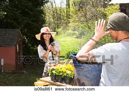 Woman spraying man with hosepipe View Large Photo Image Stock Image - Woman spraying man with hosepipe. Fotosearch