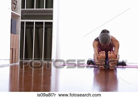 Woman stretching legs holding soles of feet View Large Photo Image Stock Photography - Woman stretching legs holding soles of feet. Fotosearch