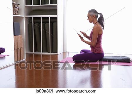 Woman using digital tablet sitting cross legged View Large Photo Image Stock Image - Woman using digital tablet sitting cross legged. Fotosearch