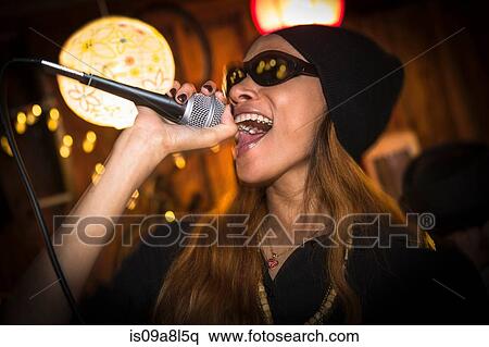 Woman wearing hat and sunglasses singing in microphone View Large Photo Image Stock Photography - Woman wearing hat and sunglasses singing in microphone. Fotosearch
