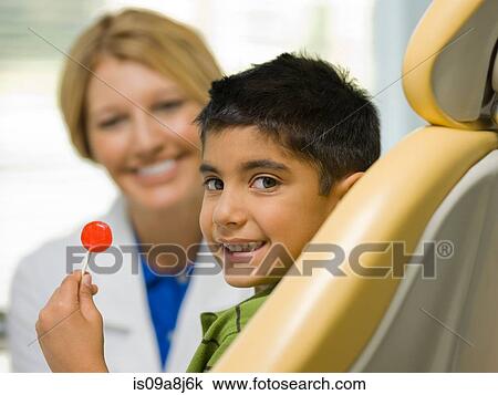 Young boy holding lollipop at the dentist's office, portrait View Large Photo Image Stock Image - Young boy holding lollipop at the dentist's office, portrait. Fotosearch