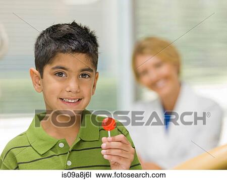 Young boy holding lollipop at the dentist's office, portrait View Large Photo Image Stock Image - Young boy holding lollipop at the dentist's office, portrait. Fotosearch