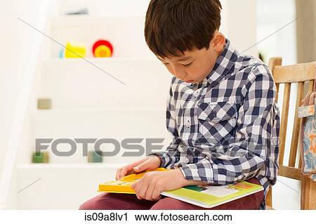Young boy sitting on chair studying game View Large Photo Image Stock Image - Young boy sitting on chair studying game. Fotosearch