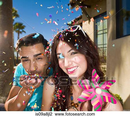 Young couple blowing confetti and smiling, portrait View Large Photo Image Stock Image - Young couple blowing confetti and smiling, portrait. Fotosearch