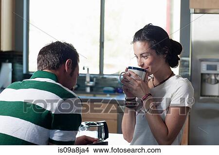 Young couple enjoying coffee in kitchen, smiling View Large Photo Image Picture - Young couple enjoying coffee in kitchen, smiling. Fotosearch