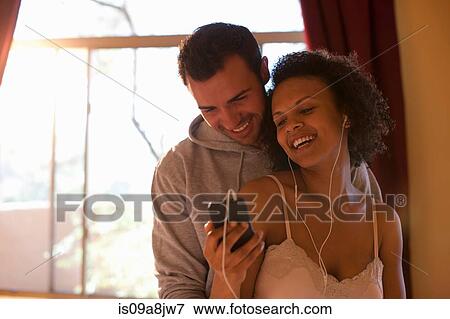 Young couple listening to mp3 player in hotel room, smiling View Large Photo Image Stock Photo - Young couple listening to mp3 player in hotel room, smiling. Fotosearch