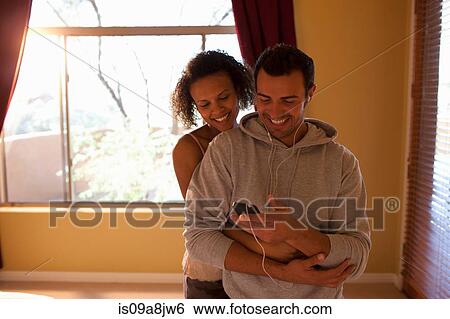 Young couple listening to mp3 player in hotel room, smiling View Large Photo Image Stock Photograph - Young couple listening to mp3 player in hotel room, smiling. Fotosearch