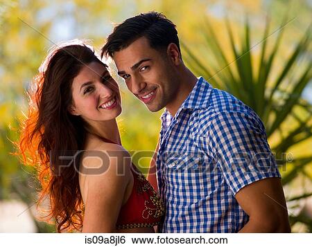 Stock Photograph - Young couple looking at camera, smiling. Fotosearch