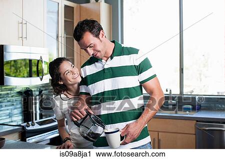 Young couple pouring coffee from pot in kitchen, smiling View Large Photo Image Stock Image - Young couple pouring coffee from pot in kitchen, smiling. Fotosearch