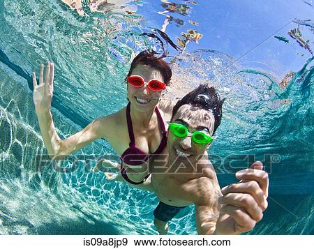 Young couple swimming underwater in pool View Large Photo Image Stock Photo - Young couple swimming underwater in pool. Fotosearch