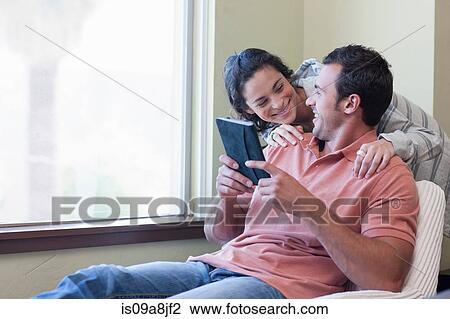 Young couple using electronic book, smiling View Large Photo Image Stock Image - Young couple using electronic book, smiling. Fotosearch