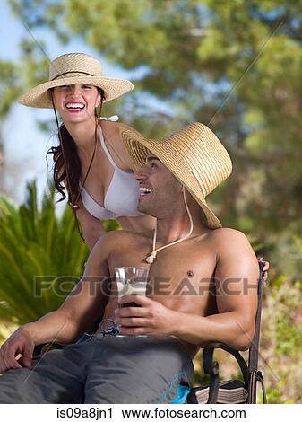Stock Image - Young couple wearing sun hats and relaxing on vacation, portrait. Fotosearch