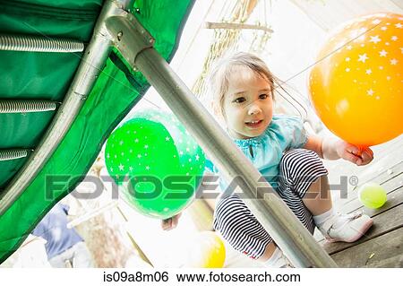 Stock Photograph - Young girl crouching with balloons. Fotosearch