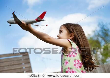 Young girl in garden playing with toy airplane View Large Photo Image Stock Image - Young girl in garden playing with toy airplane. Fotosearch