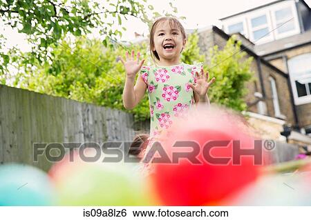 Stock Photograph - Young girl playing in garden with colored balls. Fotosearch